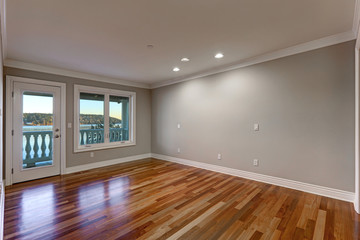 Empty room with hardwood floor and door to balcony.