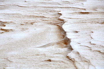 Natural background. Sandy surface with curved forms covered with snow in winter.