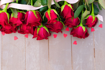 Dark Red buds of valentines day roses flowers border on wood with ribbon and hearts