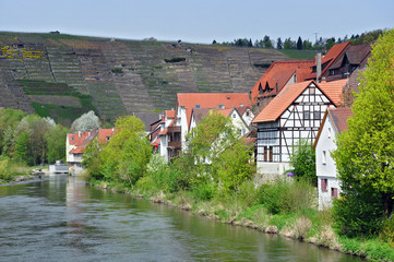 Riverside with half-timbered houses and trees on the background of mountain and the stormy sky. Besigheim, Baden-Wurttemberg, Germany.