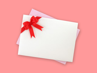 white envelope decorate with red ribbon bow and purple invitation or greeting card isolated on pink