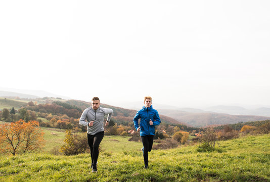Two young hipster athletes running in sunny autumn nature