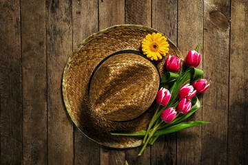 Straw hat with bunch of purple tulip flowers on vintage wooden t