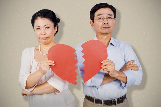 Composite image of couple holding broken heart