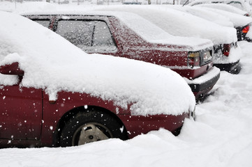 Many parked cars covered with snow after snowfall in winter. Side view.