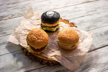 Three burgers on wooden background. Hamburgers with sesame buns. Tasty food at lowest price.