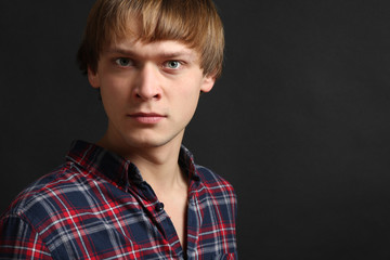 Portrait of strict young guy on a black background.