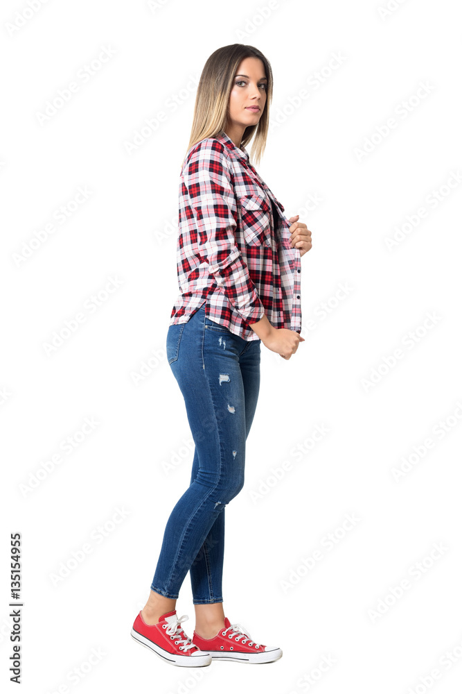 Wall mural Confident casual street style woman posing holding plaid shirt collar. Full body length portrait isolated over white studio background.