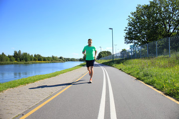 Running sport man. Fit muscular young male runner sprinting at great speed outdoors on road.