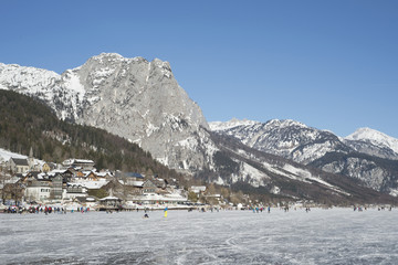 Eissportler am Grundslsee, dahinter Backenstein und weiße Wand
