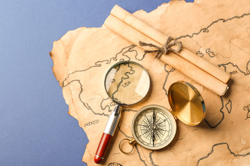 Fototapeta na wymiar Compass, scroll, magnifier and old map on blue background. Columbus Day concept