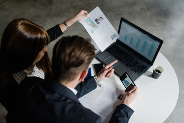 Two young business people interpreting the data sheets