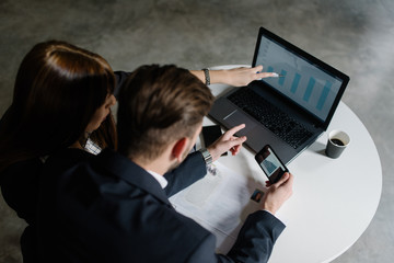Young female professional pointing at the chart on the laptop