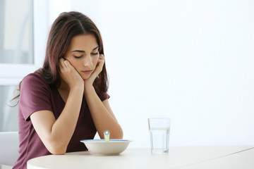 Depressed woman sitting at kitchen table without appetite