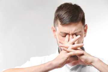 Young man with headache on white background