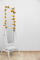 Mirror decorated with beautiful flowers near white wall