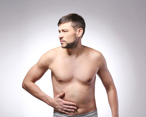 Fototapeta na wymiar Young man with stomach pain on color background