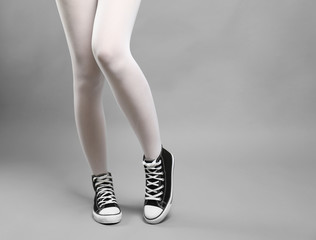 Woman in white stockings and sneakers on color background