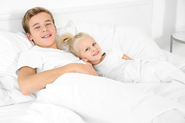 Cute little girl with elder brother lying in bed