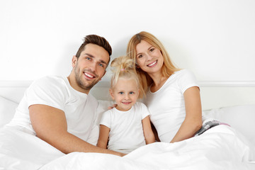 Fototapeta na wymiar Cute happy family lying in bed at home