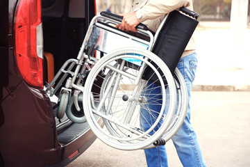 Man loading wheelchair of handicapped person