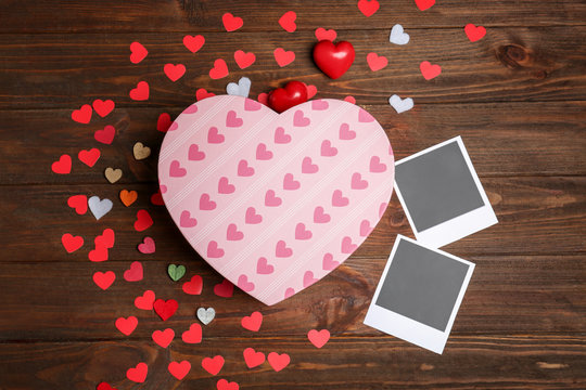 Gift box, photos and decorative hearts on wooden background