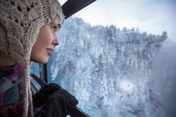 Pretty, young woman admiring splendid winter scenery from a cableway