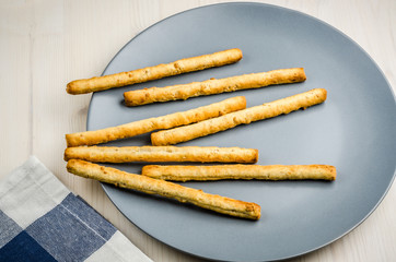 rustic breadsticks in a dish on wood table, close up, background