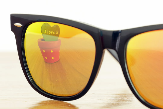 orange mirrored sunglasses with reflection of "I love you" text on the flower pot