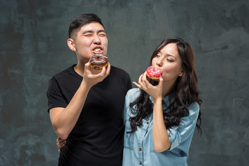 Young asian couple enjoy eating of sweet colorful donut