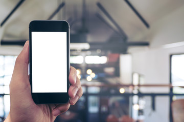 Mockup image of hand holding black mobile phone with blank white screen in cafe