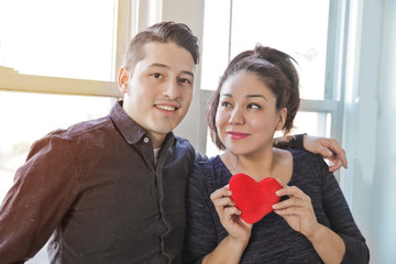 Latin couple of lovers hugging and holding Heart toy in Valentin