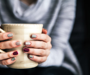 Close-up of a woman's hand holding a cup of hot coffee. fashion, leisure