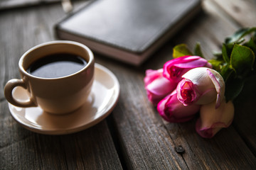 Fresh roses with diary and cup of coffee on wooden table, top view. flowers, hot drink