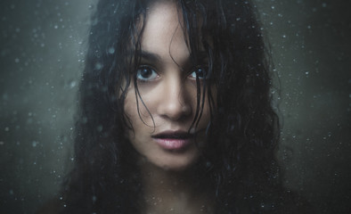 Girl staring through rainy glass