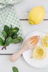 Frische Minze und Zitronen mit einem karierten Geschirrtuch auf einem weissen Holzuntergrund