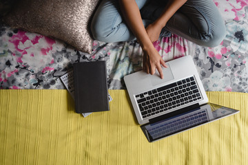 Teen girl using laptop in bedroom