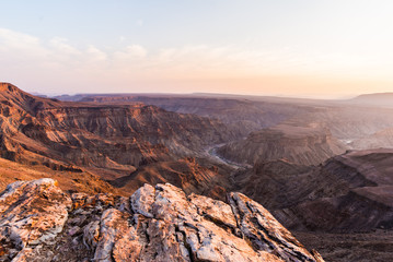 Fototapeta na wymiar Fish River Canyon, scenic travel destination in Southern Namibia. Last sunlight on the mountain ridges. Wide angle view from above.