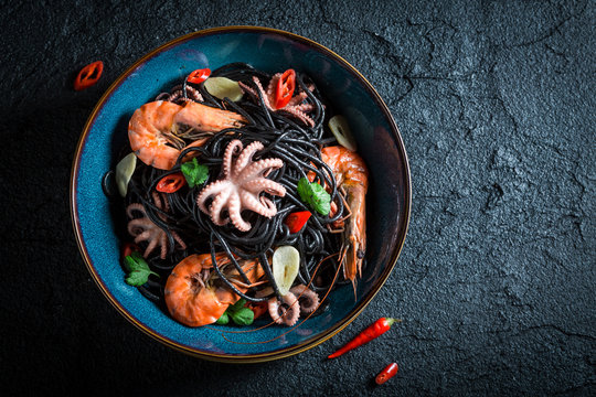 Delicious seafood black pasta with shrimp, octopus and parsley
