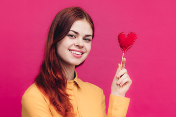 happy woman with a beautiful smile holds a heart on a stick