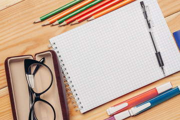 glasses in a case and a notebook with pencils