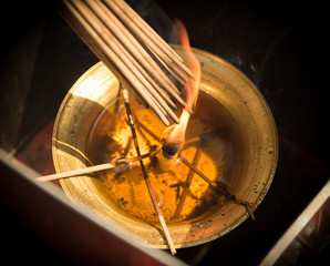 Photo of Smoke Sticks Burning Out in Gold Bowl with Fire. Asian Religion Aroma Sticks for Praying