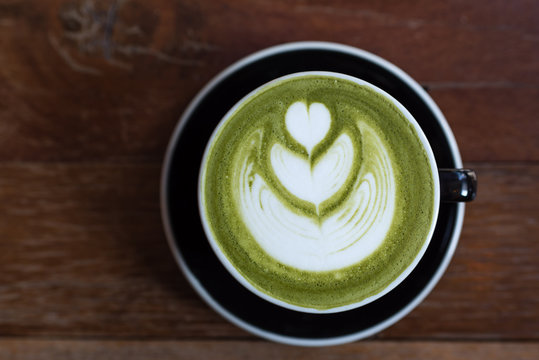 matcha green tea latte with heart shape latte art on wooden table