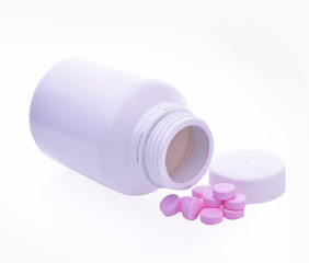 Pills spilling out of pill bottle on white background