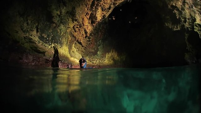 Underwater shoot of freediver ascending from the sea bottom inside the underwater cave. High level of noise, iso 800