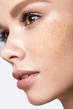 Beautiful young girl with tone powder on the skin. Beauty face. Picture taken in the studio on a white background.
