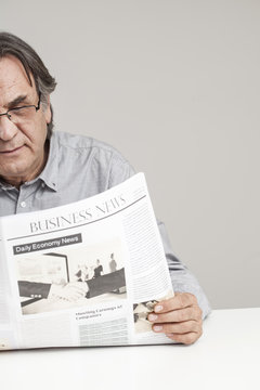 Senior man reading newspaper on table