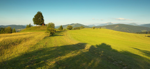 Panoramic view of a meadow with a small chapel and mountains  in Slovakia