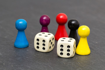 Bunte Holzspielsteine mit Würfel auf Schieferplatte