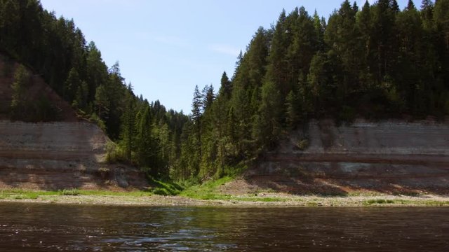 Beautiful view of forest and steep coast river in summer. Rocks of Permian outcrop on banks of river